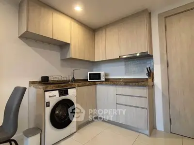 Modern kitchen with washing machine and microwave in sleek cabinetry
