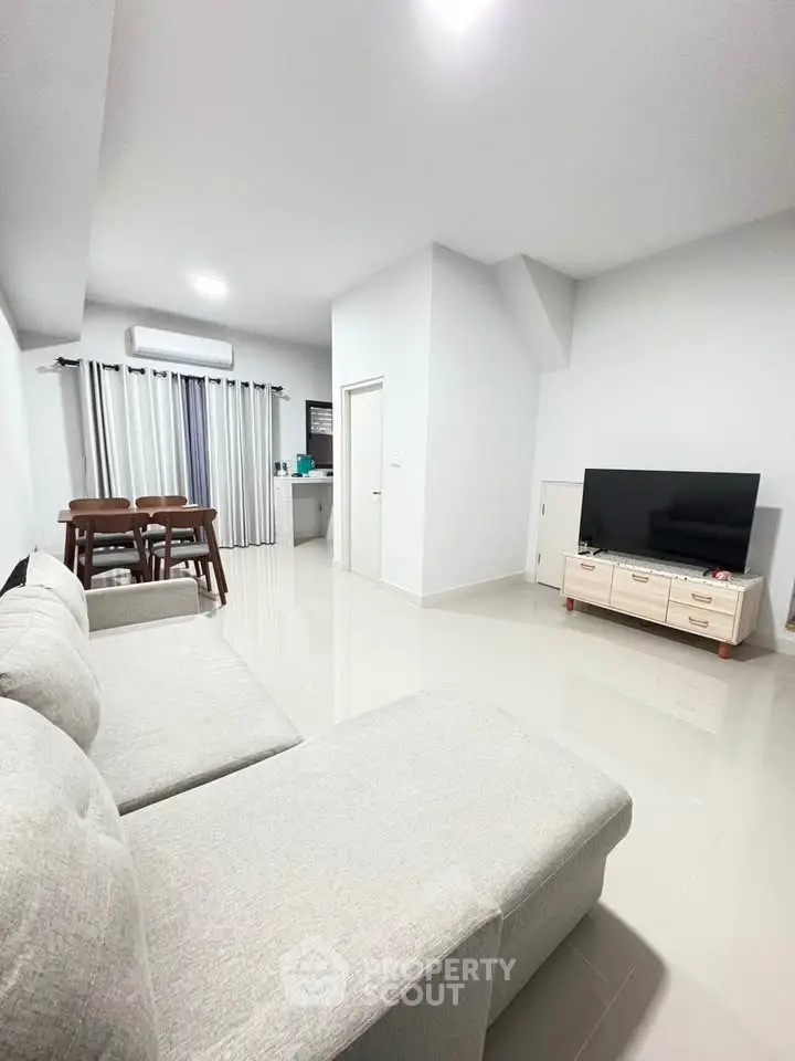 Spacious modern living room with sleek furniture and dining area, perfect for family gatherings.