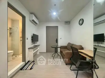 Modern living room with cozy sofa, wall-mounted TV, and adjacent bathroom in a stylish apartment.