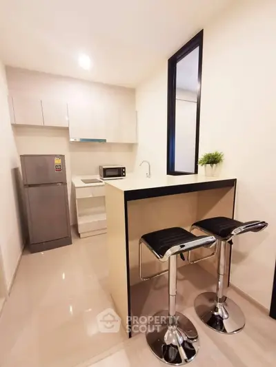 Modern compact kitchen with sleek bar stools and stainless steel appliances