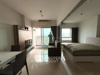 Modern studio apartment with balcony and city view, featuring sleek furniture and ample natural light.