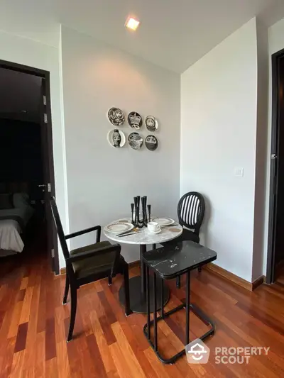 Charming dining nook with elegant black table set, decorative plates on wall, and rich wooden flooring, perfect for intimate meals in a cozy setting.