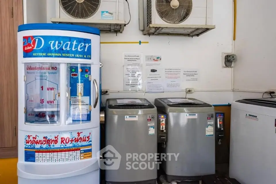 Laundry area with washing machines and water dispenser in shared building space.