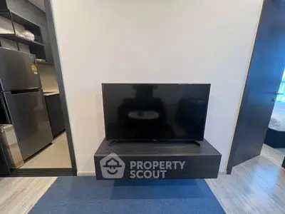 Modern living room with sleek TV setup and open kitchen view.