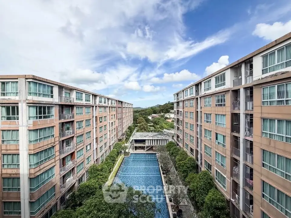 Stunning aerial view of modern apartment complex with central swimming pool and lush greenery.