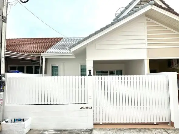 Charming single-story house with white picket fence and modern roof design.