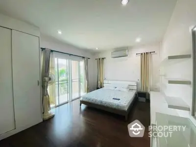 Spacious bedroom with balcony access and modern furnishings in a bright, airy apartment.