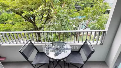 Charming balcony with lush garden view and cozy seating area.