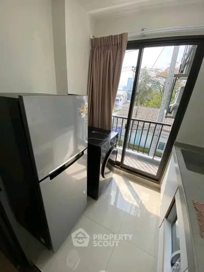 Compact kitchen with fridge and washing machine, featuring a balcony view.