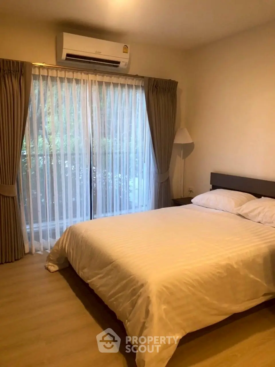 Cozy bedroom with large window and air conditioning, perfect for relaxation.