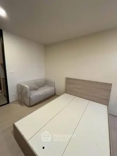 Modern bedroom with minimalist design featuring a bed frame and a sofa, ideal for urban living.