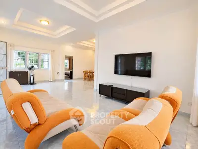 Spacious modern living room with stylish orange sofas and wall-mounted TV, perfect for relaxation and entertainment.