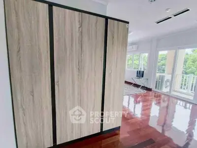 Spacious interior with wooden wardrobe and polished floors, featuring a bright balcony view.