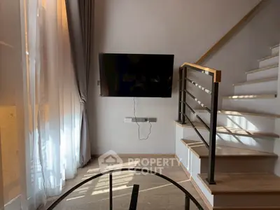Modern living room with wall-mounted TV and stylish staircase