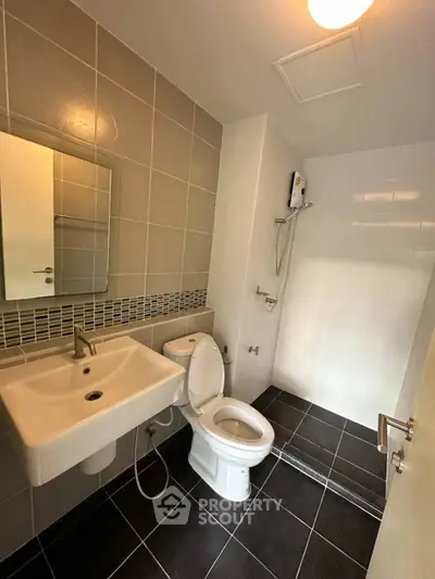 Modern bathroom with sleek fixtures and tiled walls, featuring a shower and toilet.