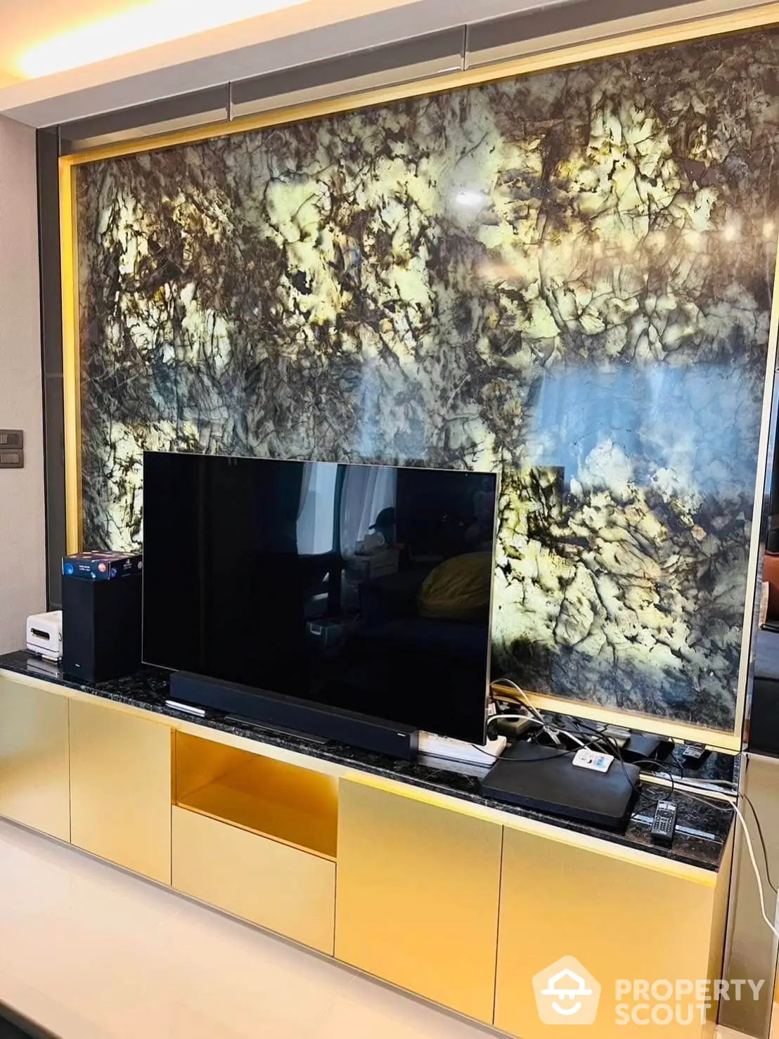 Luxurious living room with a large flat-screen TV set against a stunning marble feature wall, complemented by chic yellow cabinetry for a modern aesthetic.