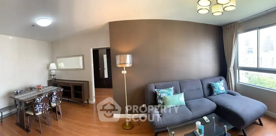 Modern living room with stylish decor and large window offering city views.