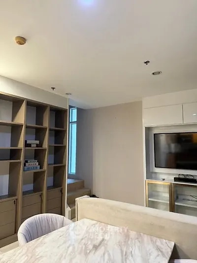 Modern living room with built-in shelves and TV unit, featuring elegant marble table.