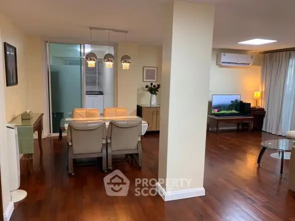 Spacious living and dining area with elegant wooden flooring and modern decor.