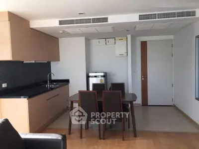 Modern kitchen and dining area with sleek cabinetry and integrated appliances in a stylish apartment.