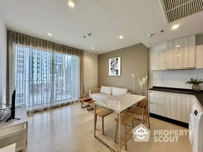 Modern open-layout living room with kitchen, featuring sleek furniture and large windows.