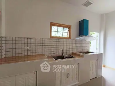 Modern kitchen with tiled backsplash and dual sinks in a bright, airy space.