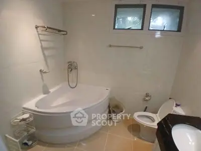 Spacious bathroom with corner bathtub and modern fixtures.