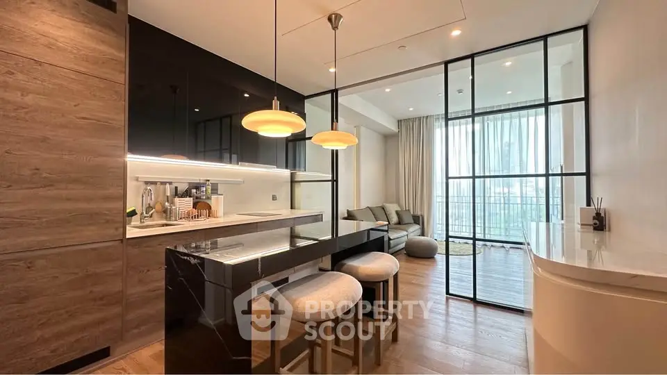 Modern open-layout kitchen with sleek black cabinetry and cozy living area, featuring stylish pendant lighting.