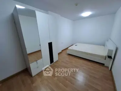 Spacious minimalist bedroom with wooden flooring and modern furniture