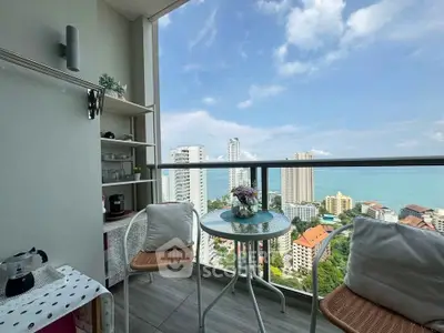 Charming balcony with ocean view, cozy seating, and modern decor in high-rise apartment.