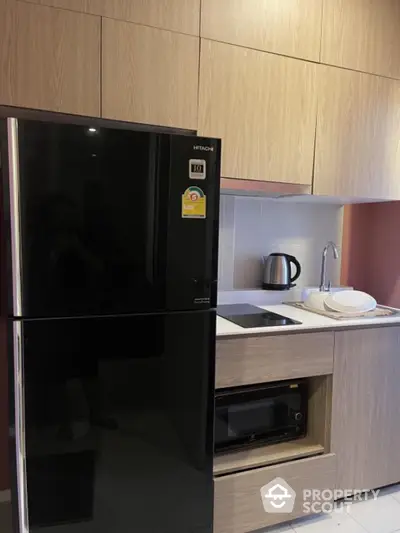 Modern kitchen with sleek black fridge, microwave, and wooden cabinets