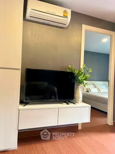 Modern living room with sleek TV stand and air conditioning, leading to a cozy bedroom.