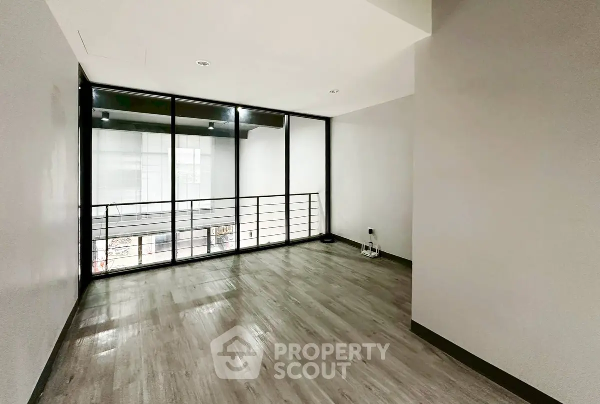 Spacious modern room with large windows and sleek flooring, perfect for versatile use.