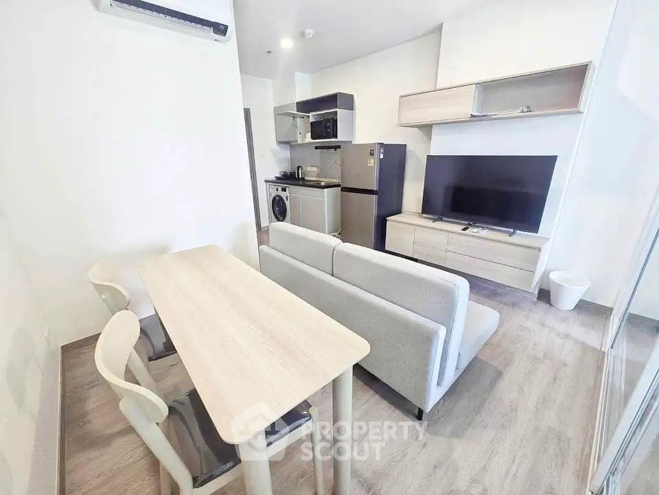 Modern open-plan living room with kitchen, featuring sleek furniture and appliances.