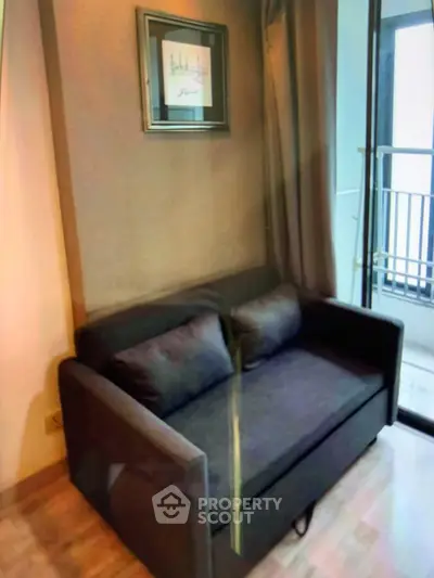 Cozy living room with modern sofa and balcony access, perfect for relaxation and enjoying natural light.