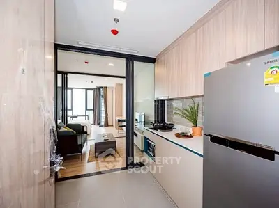 Modern kitchen with sleek appliances and open layout leading to stylish living room.