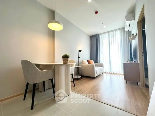 Modern living room with cozy seating and dining area, featuring natural light and stylish decor.