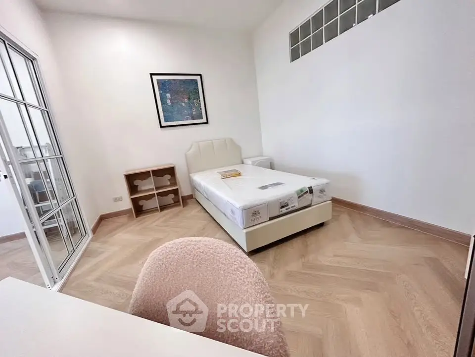 Spacious bedroom with modern decor and natural light, featuring a comfortable bed and stylish flooring.