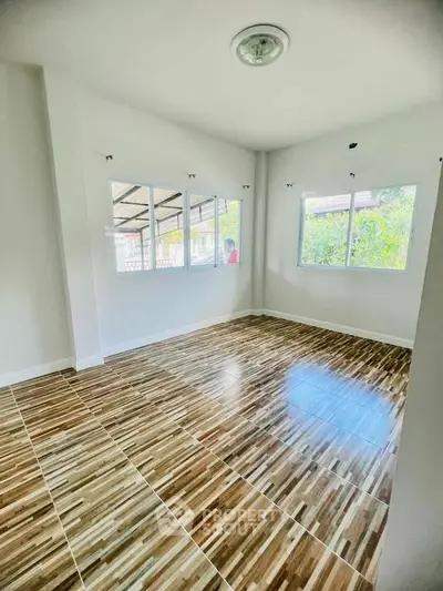 Spacious room with stylish wooden flooring and large windows for natural light.