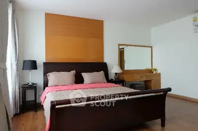 Spacious bedroom with elegant wooden furniture and natural light.