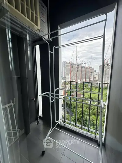 High-rise apartment balcony with city view and drying rack, perfect for urban living.