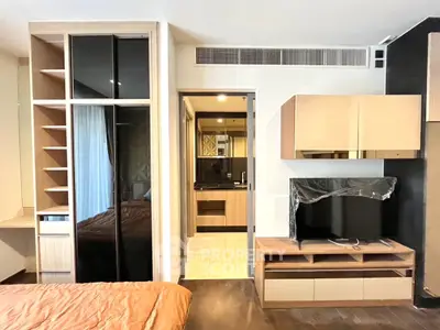 Modern bedroom with built-in closet and TV unit, featuring sleek design and warm tones.