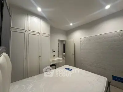 Spacious bedroom with white built-in wardrobes and modern lighting.