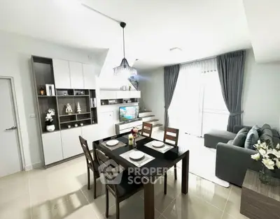 Modern living room with dining area, stylish furniture, and natural light from large windows.