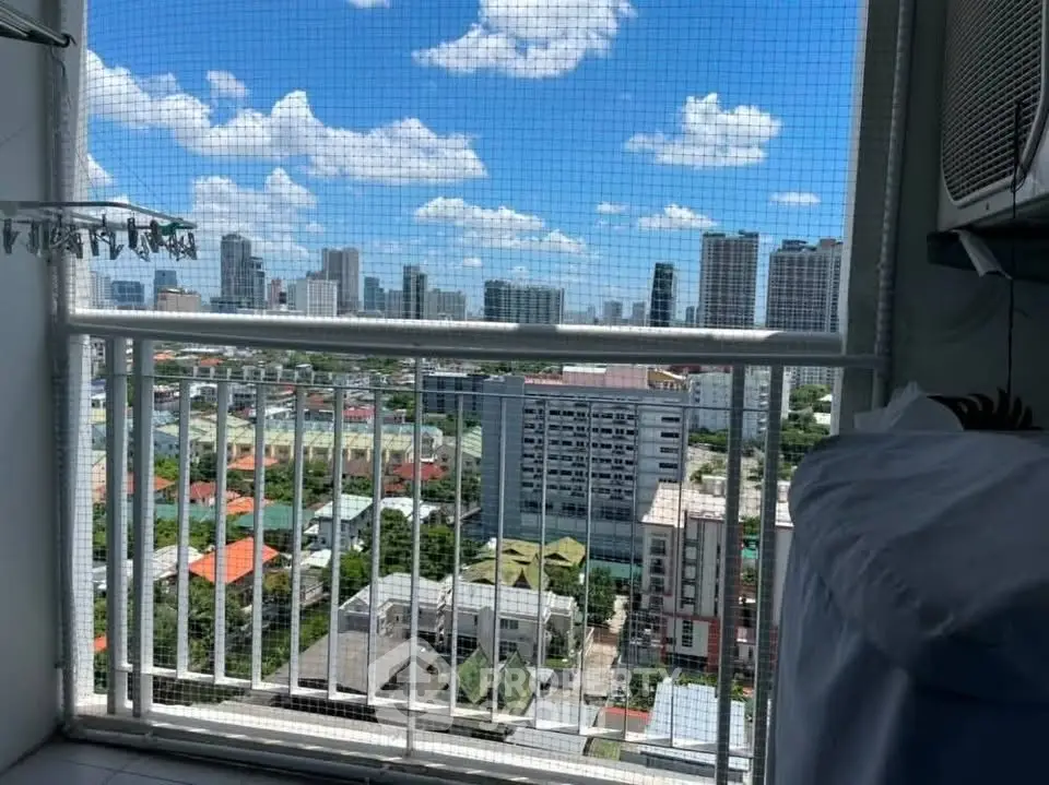 Stunning cityscape view from a high-rise balcony with safety netting and clear blue skies.