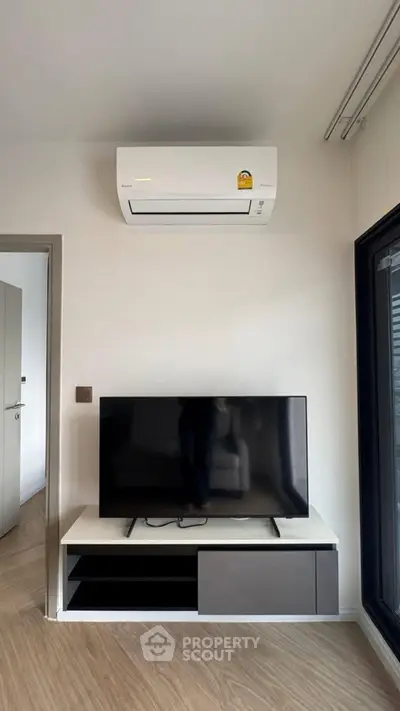 Modern living room with sleek TV setup and air conditioning unit, perfect for comfortable living.