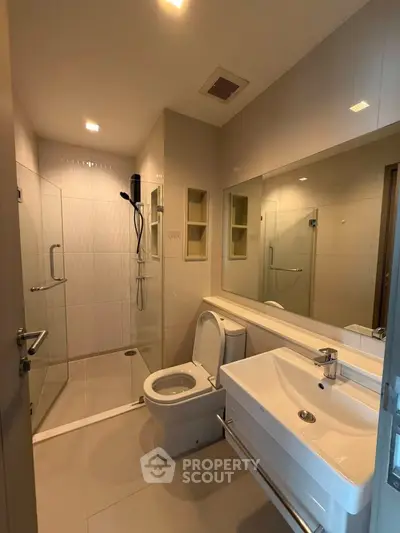 Modern bathroom with glass shower and sleek fixtures in a contemporary apartment.