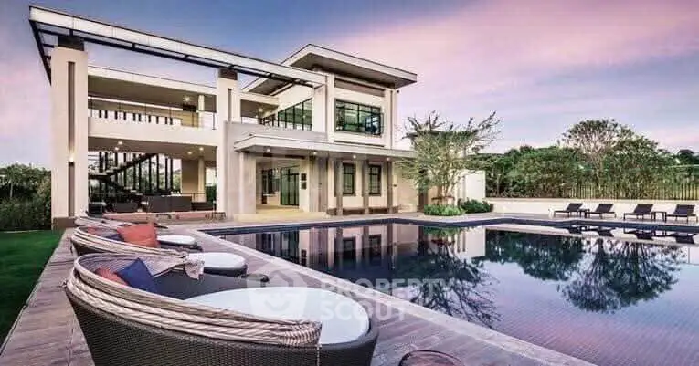 Luxurious modern villa with stunning pool and outdoor seating at sunset, perfect for upscale living.