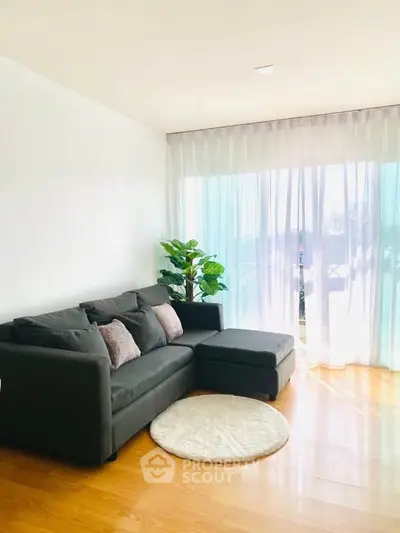 Bright living room with modern sofa and large window, perfect for relaxation.