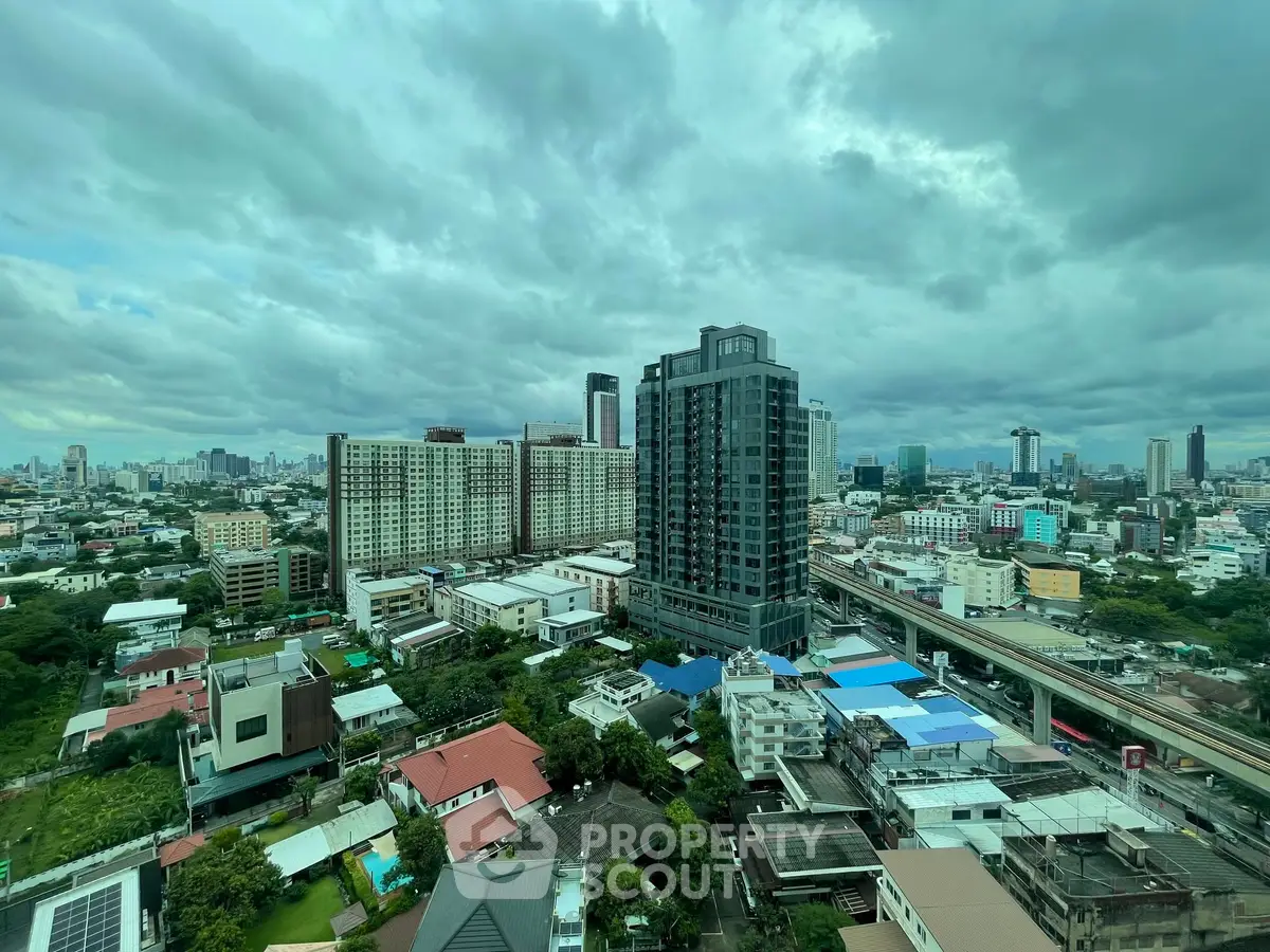 Stunning cityscape view showcasing modern high-rise buildings and lush greenery under a dramatic cloudy sky.